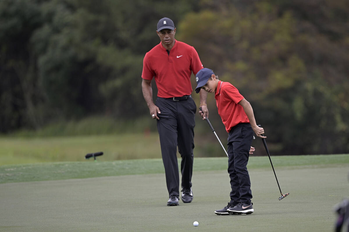 Tiger Woods watches as his son Charlie misses a putt on the 12th green during the final round o ...