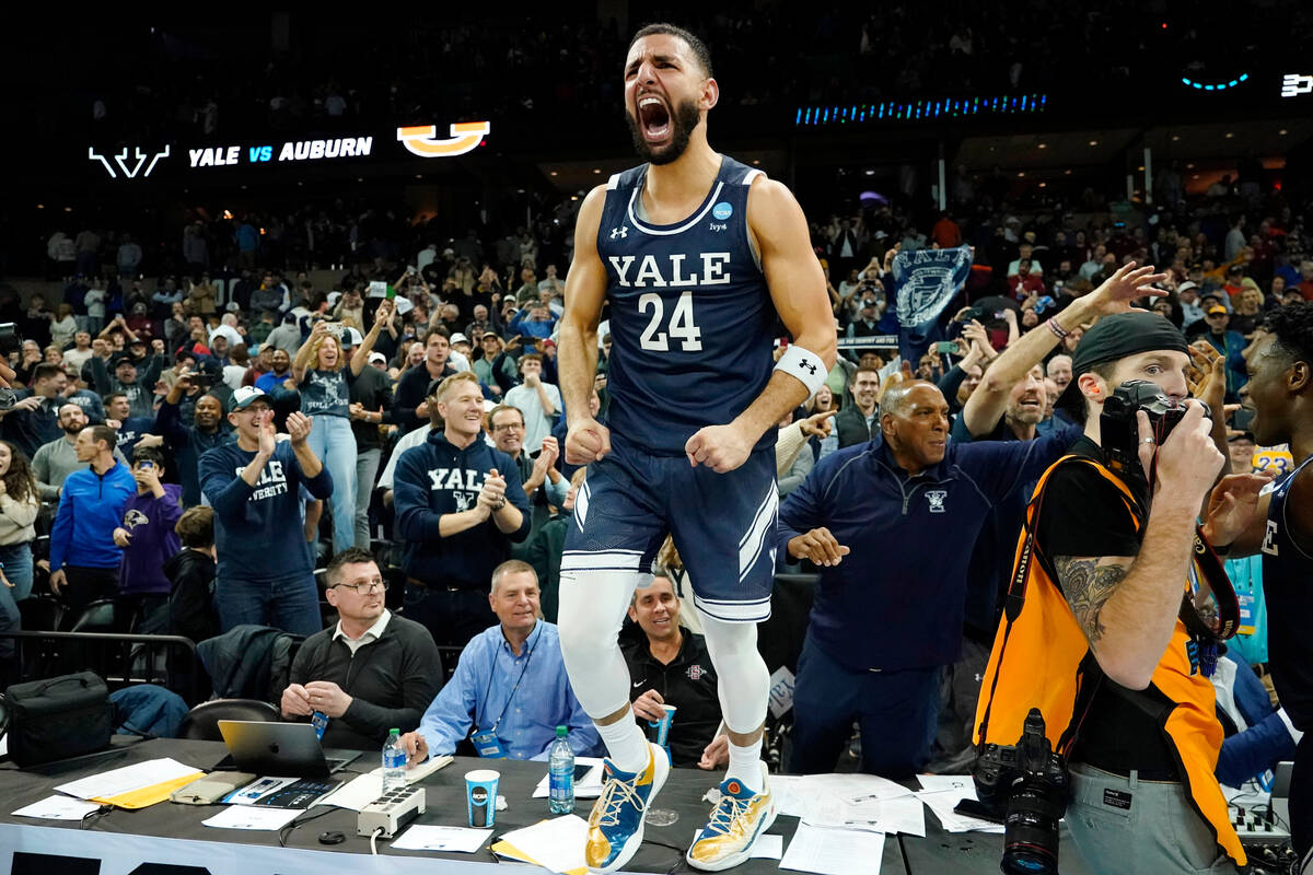Yale guard Yassine Gharram (24) stands on a table after celebrating with fans after Yale upset ...